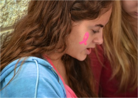 A student shows her support for breast cancer research with a pink shirt and a ribbon painted on her cheek. Students who wore pink Oct. 18 should consider doing more for the cause. Photo by Abigail Cutler. 