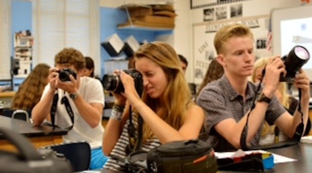 Photo students adjust cameras during class. 