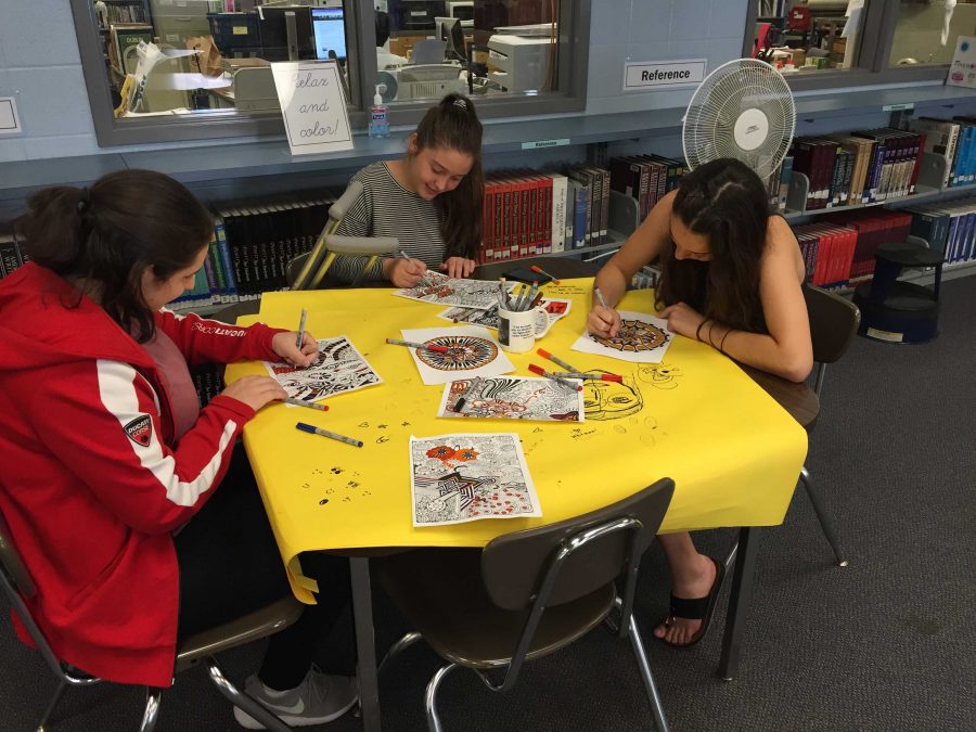 Students enjoy coloring in the media center, one of the many relaxing activities the Sources of Strength club organized to destress exam week. Photo by Avery Muir.