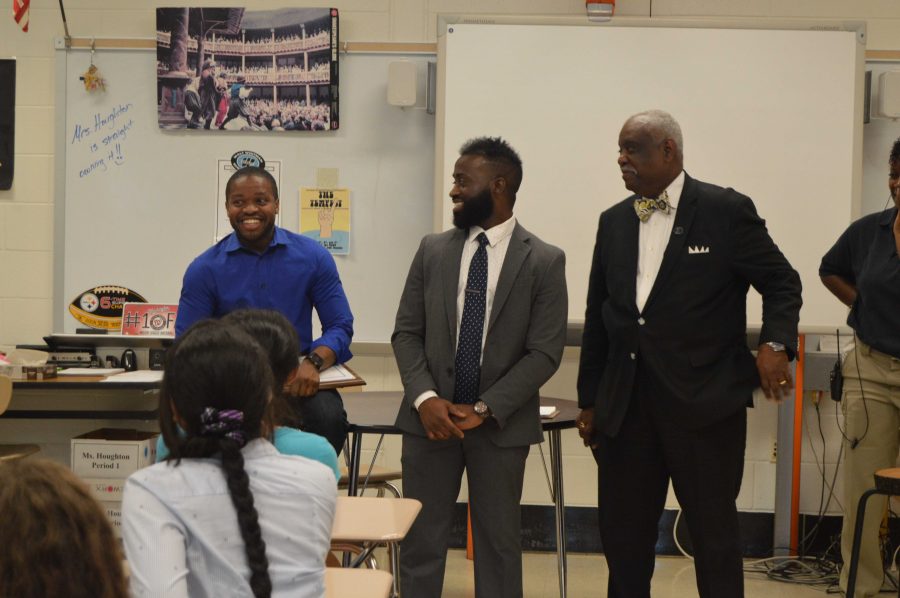 Two Phi Delta Sigma fraternity members presented English teacher Omari James with 
