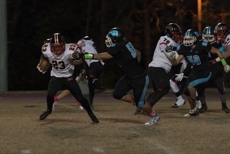 Defensive lineman Dawson Mackay looks to take down QOs running back in the backfield, with linebacker Ben Wilson trailing in pursuit. Photo by Jefferson Luo.