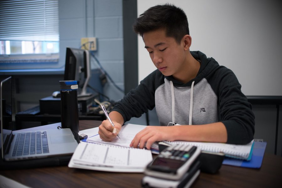 Leung completes his homework in the library. He said that at Whitman, varying classes like honors and AP mean the course load can make schoolwork more difficult. Photo by Tomas Castro. 