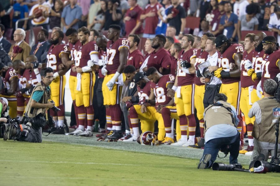 Washington Redskins players kneel and link arms during the national anthem in protest against racial injustice. The protests, inspired by Colin Kaepernick, have been heavily criticized by President Donald Trump. Photo courtesy Keith Allison.