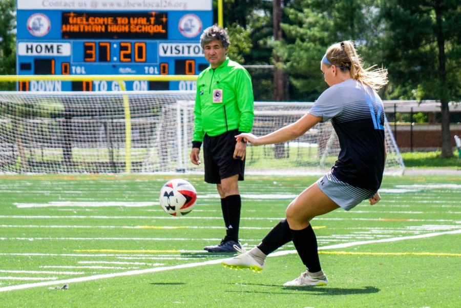 A soccer referee looks on as a Whitman player passes the ball. Recently, the number of high school soccer referees has decreased as a result of verbal abuse. 
