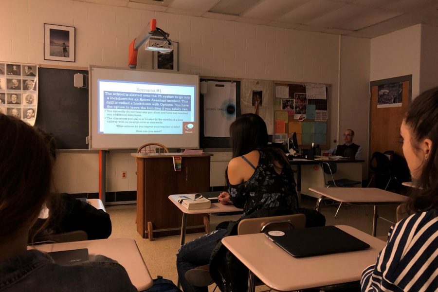 Students look on as English teacher Todd Michaels walks the class through possible scenarios under the new active assailant policy. All teachers gave the same county-provided presentation, and supplemented it with hypotheticals specific to their classrooms.