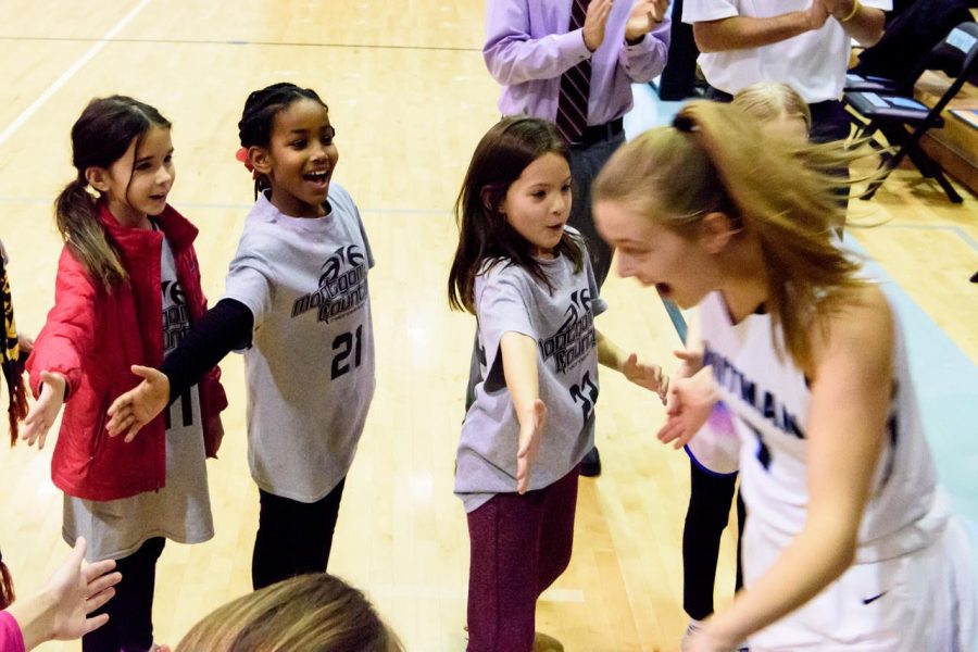Girls on a Montgomery County recreational basketball team high five Carter Witt (18) before a game. The Youth Teams program aims to expose recreational basketball teams to high school varsity basketball.