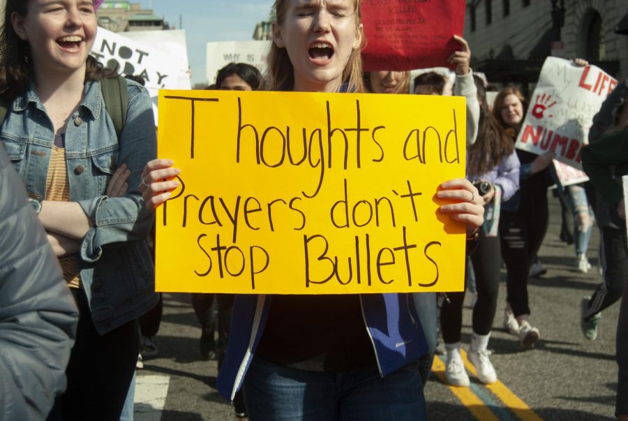 A students sign rebukes politicians lack of action coupled with condolences in response to shootings. 