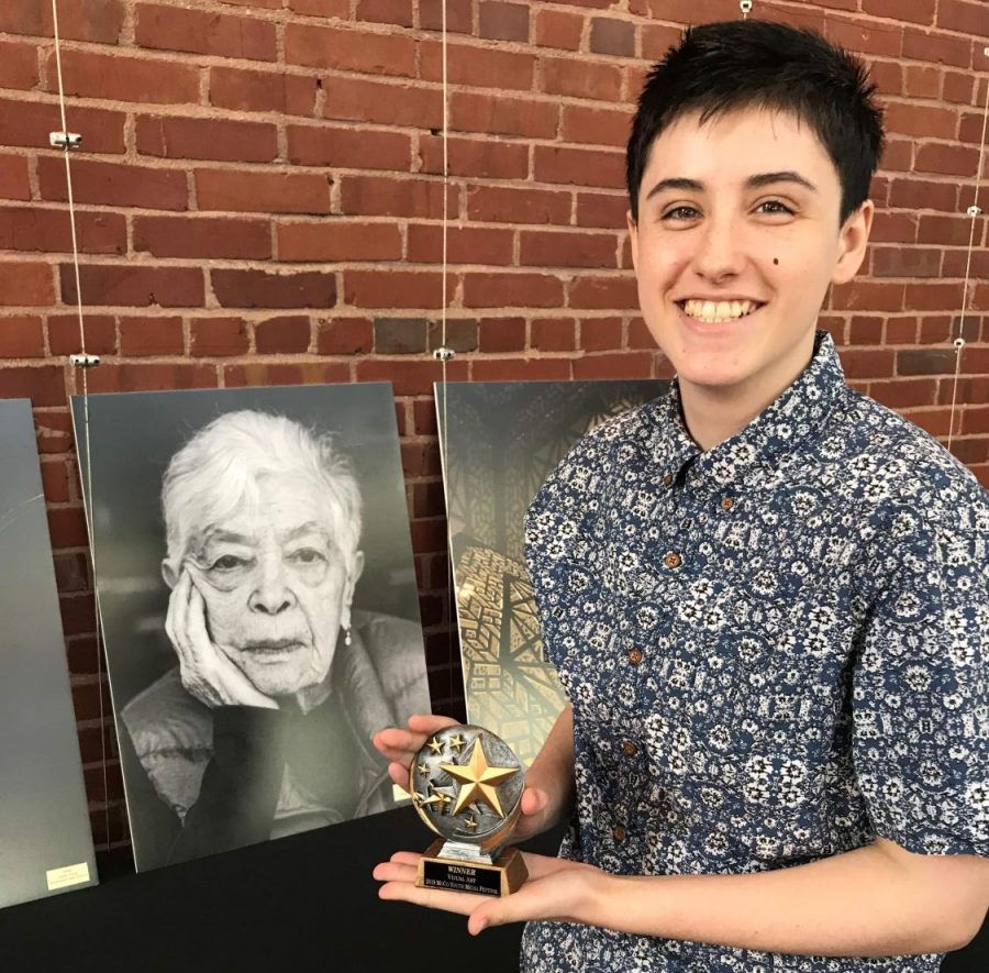 Gates holds his award as he poses next to his photo of Holocaust survivor Ruth Cohen. Gates won $100 for the picture and chose to give Cohen the final photo. Photo courtesy Lukas Gates.