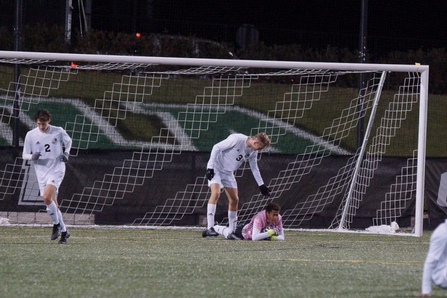 Center back Abe Hoogeveen reaches down to goalie Austin Mboijana after a save. 