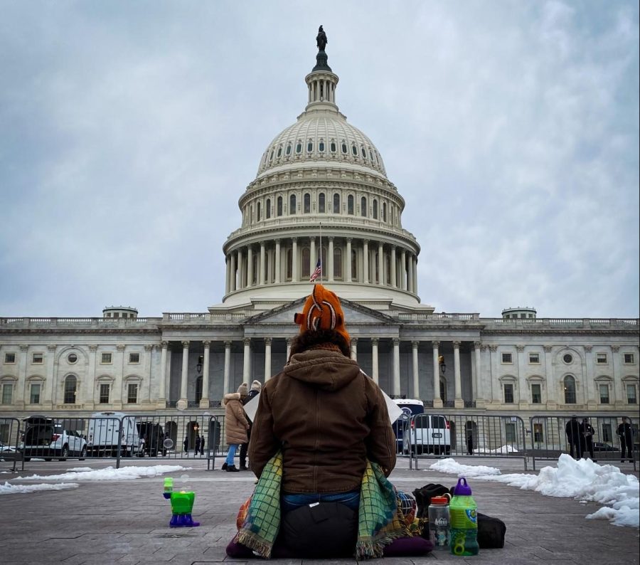 An advocate for peace meditates in front of the Capitol Building on the one-year anniversary of the insurrection.