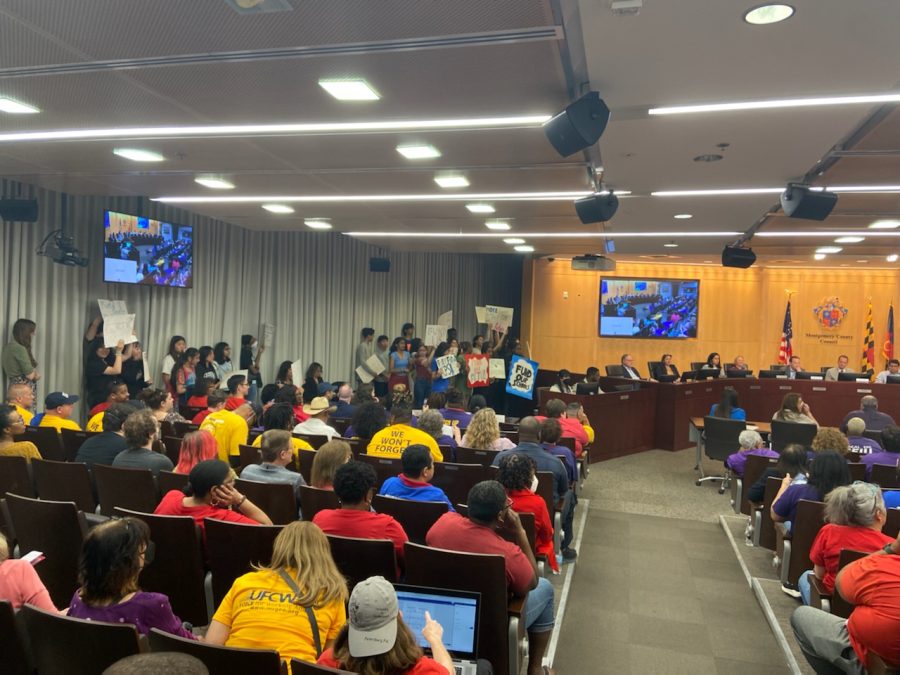 The+Montgomery+County+Council+conducts+a+public+hearing+about+the+proposed+budget+while+MCPS+students+hold+signs+in+a+show+of+support+for+the+measure.