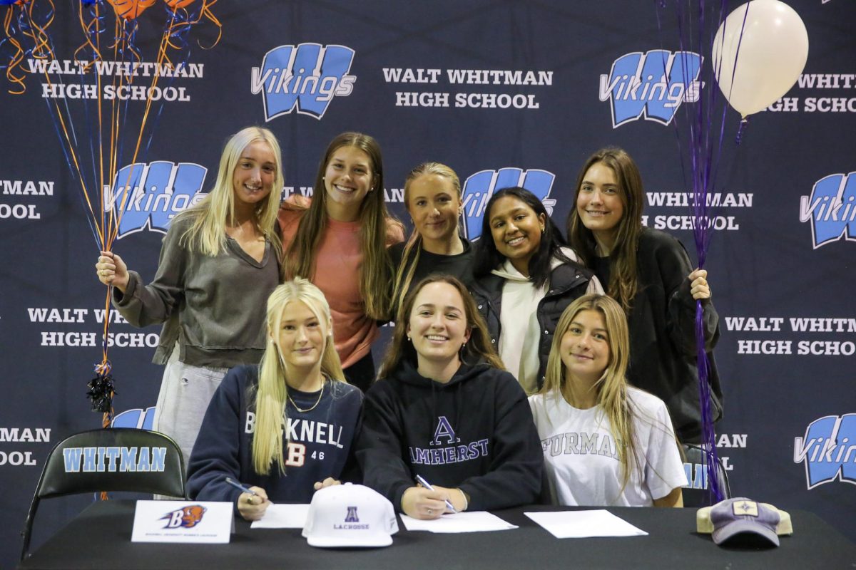 Committed athletes from the women’s lacrosse team pose for a photo with team members at Signing Day.